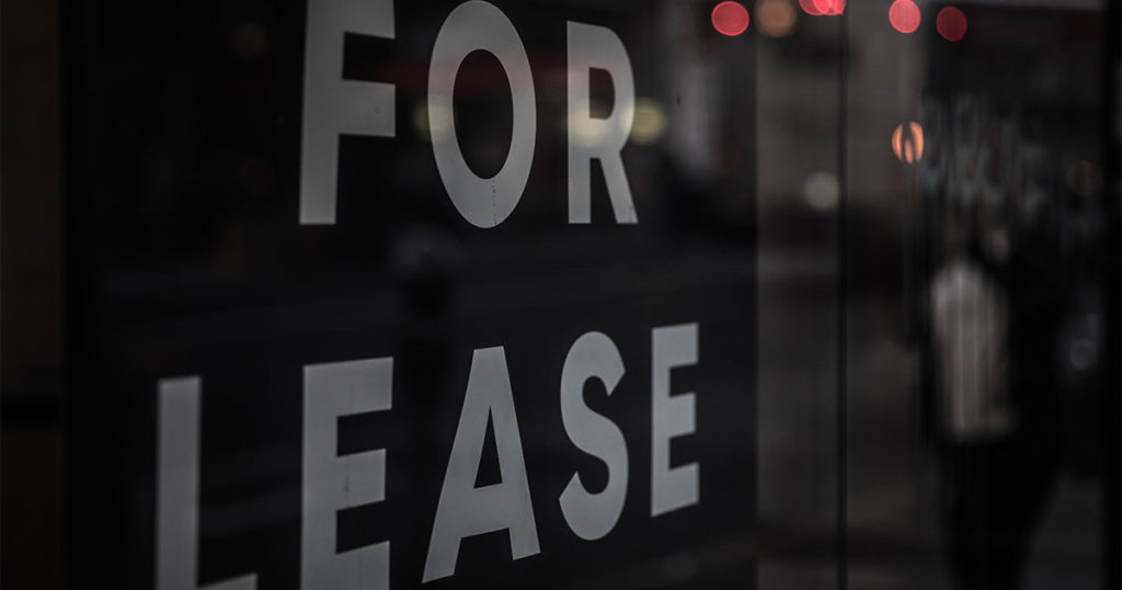  A vacant storefront window decal says there’s commercial property for lease.
