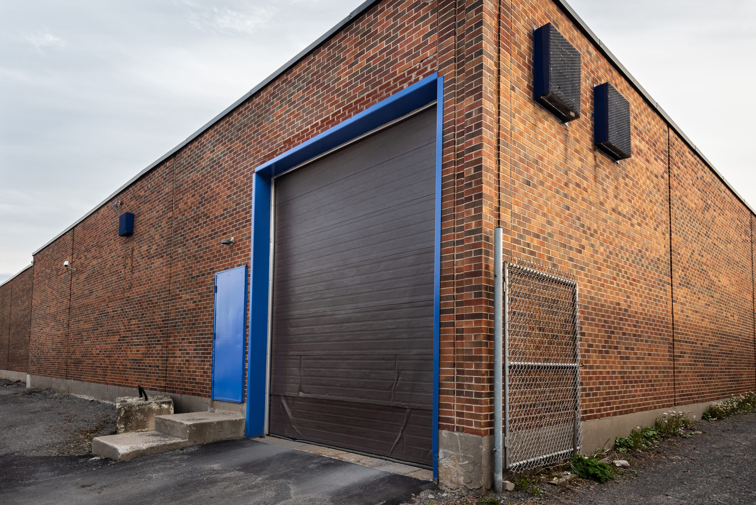 The exterior corner of a brick REO property with a loading dock. The door to the loading dock is closed.